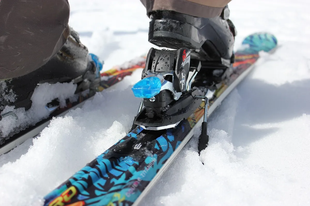But narciarski wpięty w wiązanie zjazdowe na kolorowej narcie stojącej na śniegu