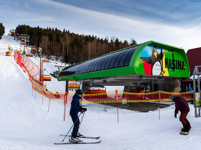 Zielona stacja kolei krzesełkowej Kasina Ski i narciarze na ośnieżonym stoku w słoneczny dzień