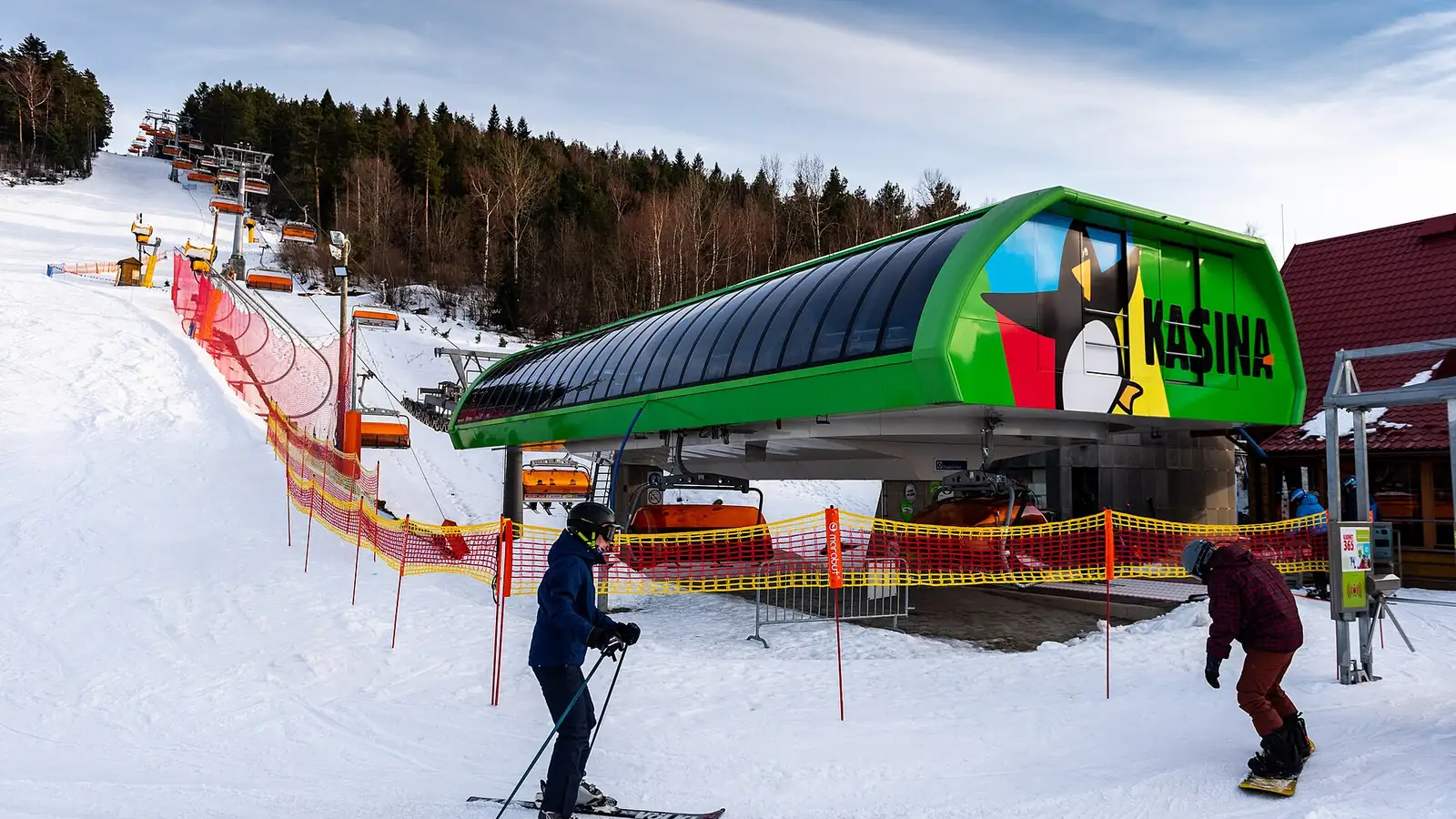 Zielona stacja kolei krzesełkowej Kasina Ski i narciarze na ośnieżonym stoku w słoneczny dzień