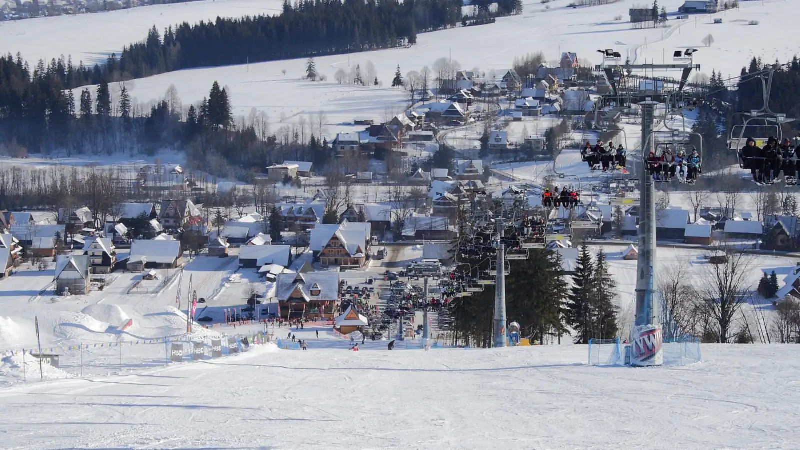 Kolej krzesełkowa nad ośnieżonym stokiem Witów-Ski, w dole zabudowa Witowa i zaśnieżone pola