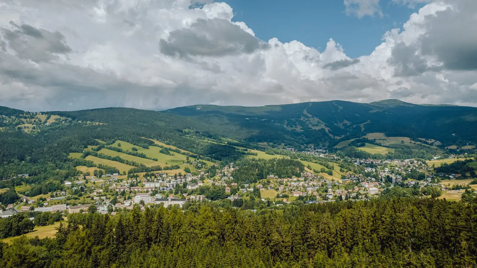 Panorama Rokytnic nad Jizerou z zalesionymi zboczami Lysej hory i Kotla w Karkonoszach pod chmurami