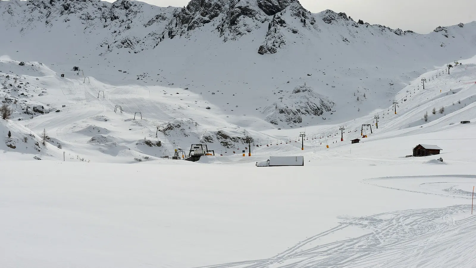 Szerokie ośnieżone stoki i wyciągi ośrodka Ciampac pod skalistym grzbietem Dolomitów